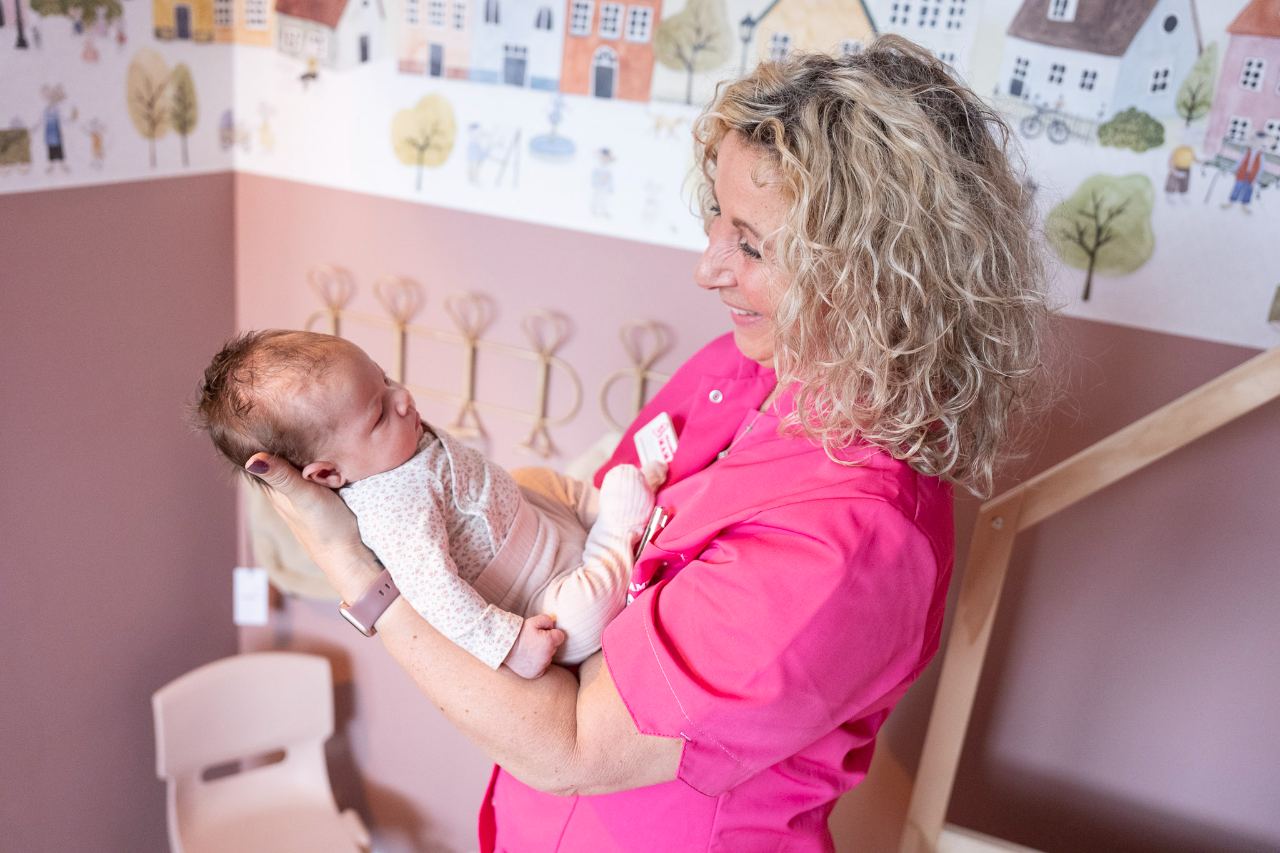 Kraamverzorgende van Kraamzorg Mama wiegt een pasgeboren baby op de babykamer